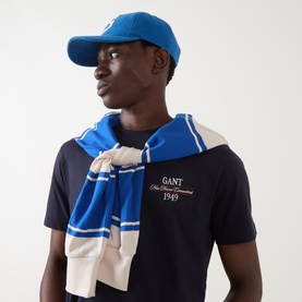 Model wearing Gant Evening Blue Crew Neck T-shirt, styled with a matching blue striped scarf and blue cap.