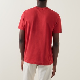 Model wearing Gant 1949 Logo T-Shirt in Maple Fire, rear view, crew neck, short sleeves, styled with white trousers.