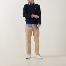 Model wearing Gant Shield Logo Micro Textured Sweater in Evening Blue crew neck, styled with blue stripe shirt, tan chinos and white trainers.