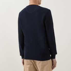 Model wearing Gant Shield Logo Micro Textured Sweater in Evening Blue, crew neck, micro textured cotton, back view, styled with beige trousers.
