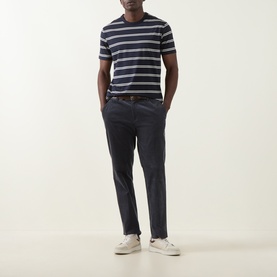 Model wearing Gant Pima Striped T-Shirt in Evening Blue with navy chinos, brown belt, and white trainers.
