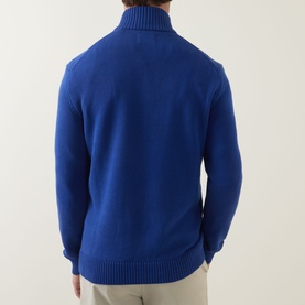 Model wearing Gant Shield Logo Half-Zip Sweater in Crisp Blue, rear view showing ribbed funnel neck, half-zip and hem trim, styled with beige