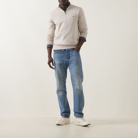 Model wearing Gant Shield Half-Zip Sweater in clay beige with blue jeans and white trainers.