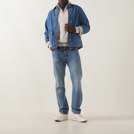 Model wearing Gant Shield Half-Zip Sweater in clay beige, styled with blue denim jacket, light wash jeans and white trainers.