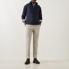 Model wearing Gant Evening Blue quilted down gilet with hood, styled with cream trousers and brown leather shoes.