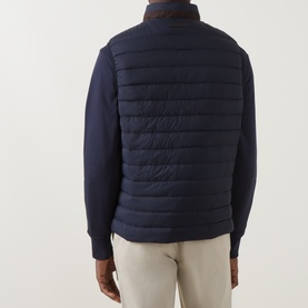 Model wearing Gant Evening Blue quilted down gilet, back view, styled with navy knit sweater and beige trousers