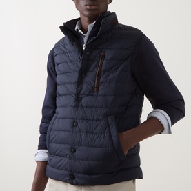 Model wearing Gant Evening Blue quilted gilet with funnel neck, zip chest pocket, and button front, styled over a blue shirt