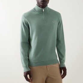 Model wearing Gant Shield Logo Half-Zip Sweatshirt in Surplus Mint, featuring half-zip funnel neck and chest logo. Styled with tan trousers.