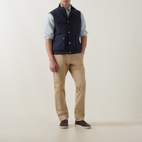 Model wearing Gant Classic Diamond Quilted Gilet in Evening Blue with light blue shirt, beige chinos and dark suede shoes.
