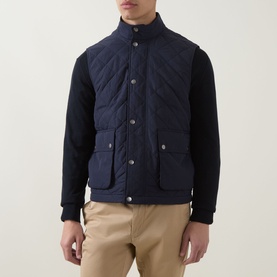 Model wearing Gant Classic Diamond Quilted Gilet in Evening Blue, styled with navy knit sleeves and beige chinos.