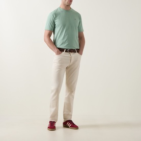Model wearing Gant Shield Logo T-Shirt in Surplus Mint with cream chinos, white belt, and burgundy Adidas trainers.