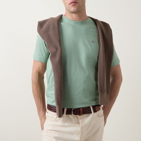 Model wearing Gant Shield Logo T-Shirt in Surplus Mint, styled with a brown gilet and beige trousers with a brown belt.