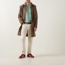 Model wearing Gant Shield Logo T-Shirt in Surplus Mint, styled with brown coat, cream trousers, and red trainers.