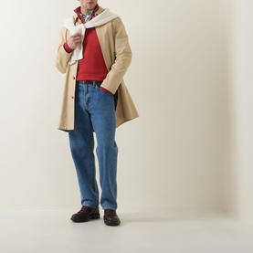 Model wearing Gant Maple Fire cotton half zip, styled with beige longline coat, blue straight-leg jeans, patterned scarf and dark loafers