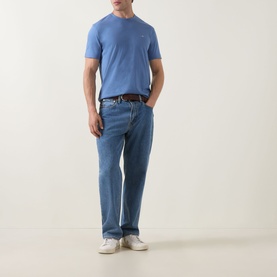 Model wearing Gant Shield Logo T-Shirt in Blue Horizon, styled with light wash jeans, dark belt and white trainers.