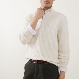 Model wearing Gant Logo Textured Half-Zip Sweater in cream, styled with a white shirt and olive trousers