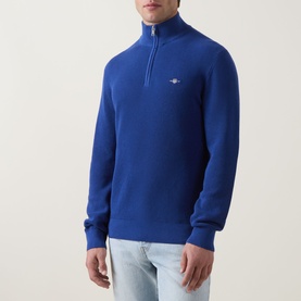Model wearing Gant Shield Logo Half-Zip Micro Textured Sweatshirt in Crisp Blue with funnel neck and ribbed trims, styled with light wash jeans.