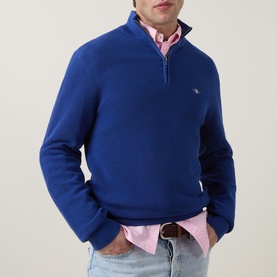 Model wearing Gant Shield Logo Half-Zip Micro Textured Sweatshirt in Crisp Blue with funnel neck, styled with pink shirt and jeans.