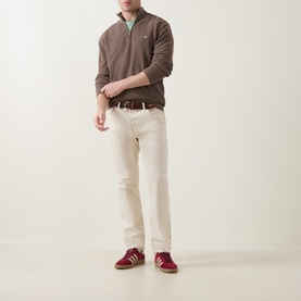 Model wearing Gant Shield Logo Half-Zip Micro Textured Sweatshirt in Dark Hazelnut Melange, styled with cream jeans and red trainers.