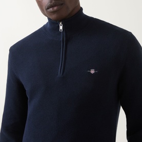 Model wearing Gant Shield Half-Zip Textured Sweater in Evening Blue, showing waffle knit texture, half-zip fastening and embroidered shield logo.