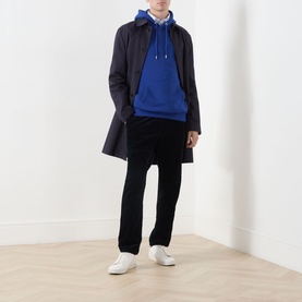 Model wearing Gant Shield Drawstring Hoodie in Crisp Blue with navy overcoat, black trousers and white trainers.