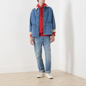 Model wearing Gant Shield Drawstring Hoodie in Maple Fire red, styled with denim jacket, light wash jeans and white trainers.