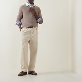 Model wearing Gant Rugby Knitted Polo Shirt in Mist Taupe with light blue shirt underneath, styled with cream trousers and brown loafers.