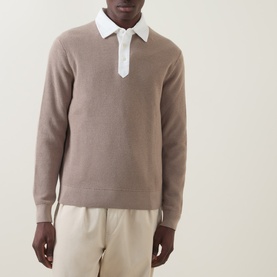Model wearing Gant Rugby Knitted Polo Shirt in Mist Taupe with white contrast collar, styled with cream trousers.
