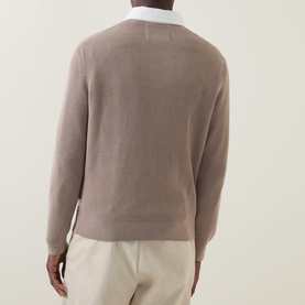 Model wearing Gant Rugby Knitted Polo Shirt in Mist Taupe, back view, with white contrast collar visible, styled with cream trousers.