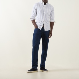 Model wearing Gant Archive Oxford Striped Shirt in cream with button-down collar, styled with navy trousers and navy canvas shoes.