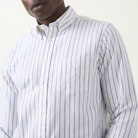 Model wearing Gant Archive Oxford Striped Shirt in cream with blue and tan stripes, button-down collar and chest pocket visible.