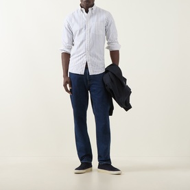 Model wearing Gant Archive Oxford Striped Shirt in cream with button-down collar, styled with dark blue jeans and navy jacket.
