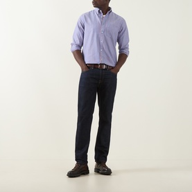 Model wearing Gant Crisp Blue striped cotton reg shirt with dark indigo jeans, brown belt, and dark hiking shoes.