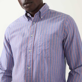 Model wearing Gant Crisp Blue striped cotton reg shirt, close-up showing button-down collar and red stripe detail