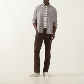 Model wearing Gant Brown Melange Reg Shirt, styled with a striped tee, dark brown trousers and white trainers.