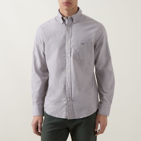 Model wearing Gant Shield Logo Oxford Shirt in faded taupe with button-down collar, chest pocket, paired with dark green trousers.