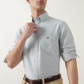 Model wearing Gant Shield Logo Oxford Shirt in Surplus Mint, button-down collar, chest pocket, styled with tan chinos and brown belt.