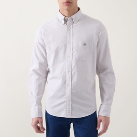 Model wearing Gant light taupe cotton reg shirt with button-down collar and chest logo, styled with blue jeans.