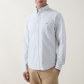 Model wearing Gant Shield Logo Striped Shirt in Surplus Mint, button-down collar, long sleeves, chest pocket, paired with beige chinos.
