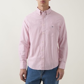 Model wearing Gant Shield Logo Striped Shirt in Maple Fire, button-down collar, chest pocket, styled with blue jeans.