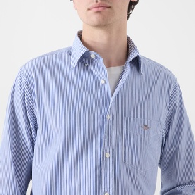Model wearing Gant Classic Stripe Banker Shirt in College Blue with white stripes, button-down collar and embroidered shield logo on chest pocket.