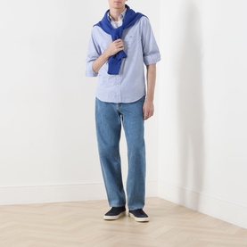 Model wearing Gant Classic Stripe Banker Shirt in College Blue with blue knit scarf draped over shoulders, styled with light-wash jeans and navy