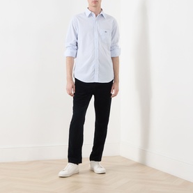 Model wearing Gant Classic Stripe Banker Shirt in light blue with black trousers and white trainers.