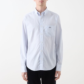 Model wearing Gant Classic Stripe Banker Shirt in light blue, button-down collar, chest pocket, paired with dark trousers.
