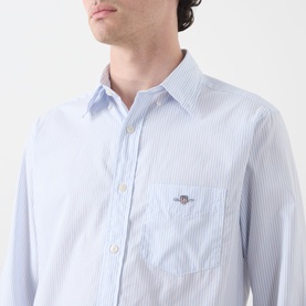 Model wearing Gant Classic Stripe Banker Shirt in light blue with white stripes, chest pocket and embroidered shield logo visible.