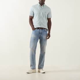 Model wearing Gant Shield Logo Shirt in Surplus Mint, short sleeves, button-down collar, styled with light wash jeans and white trainers.