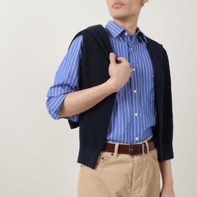 Model wearing Gant Shield Logo Striped Casual Shirt in College Blue with navy jacket draped over shoulder and beige chinos.