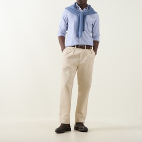 Model wearing Gant Shield Logo Striped Shirt in College Blue with button-down collar, styled with beige chinos, blue sweater tied around shoulders.