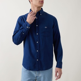 Model wearing Gant Reg Shirt in dark indigo, button-down collar, chest pocket with logo, styled with light wash jeans.