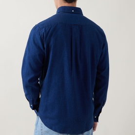 Model wearing Gant Reg Shirt in dark indigo, rear view showing box pleat, button-down collar, styled with light blue jeans.